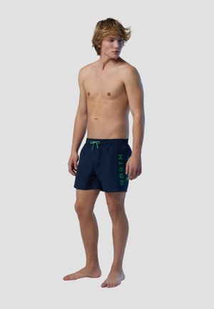 Costumi da bagno della marina con grafica verde "NORTH", vita elastica e cordoncino. Il materiale sembra leggero e adatto per attività acquatiche.