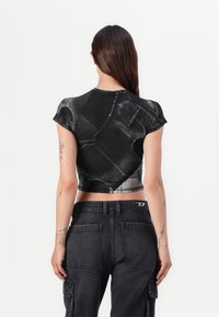 Cropped black T-shirt featuring a denim texture design. Short sleeves and fitted silhouette, paired with high-waisted black cargo pants.