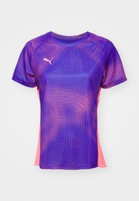 T-shirt de sport violet à manches courtes avec motif à pois roses et petit logo Puma blanc sur la poitrine gauche sur fond uni.