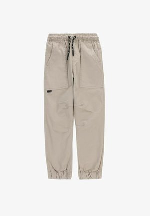 Jasnobeżowe casualowe spodnie z elastycznym pasem, czarnym sznurkiem, dwiema naszywanymi kieszeniami z przodu oraz elastycznymi ściągaczami na kostkach.