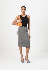 Body negru, fustă tip creion din denim gri cu detalii de cusătură, geantă portocalie și tocuri albastre cu model. Design simplu și modern.