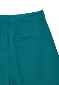 Un pantalon en lin teal présente une texture lisse, une coupe droite avec une taille, et deux poches arrière. Les coutures doubles renforcent la durabilité.