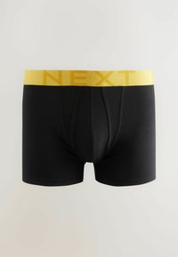 Fekete boxer alsónadrág sárga elasztikus derékkal, melyen a "NEXT" szó félkövér betűkkel szerepel. Sima tapintású és testhezálló kialakítás.