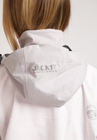 Lichtroze waterdichte jas met een capuchon en een reflecterend logo met coördinaten. Gladde textuur met zwarte mesh accenten.
