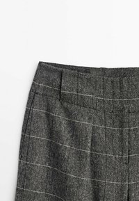 Pantalons à carreaux gris en tissu texturé, avec une taille, des plis à l'avant et des rayures blanches.