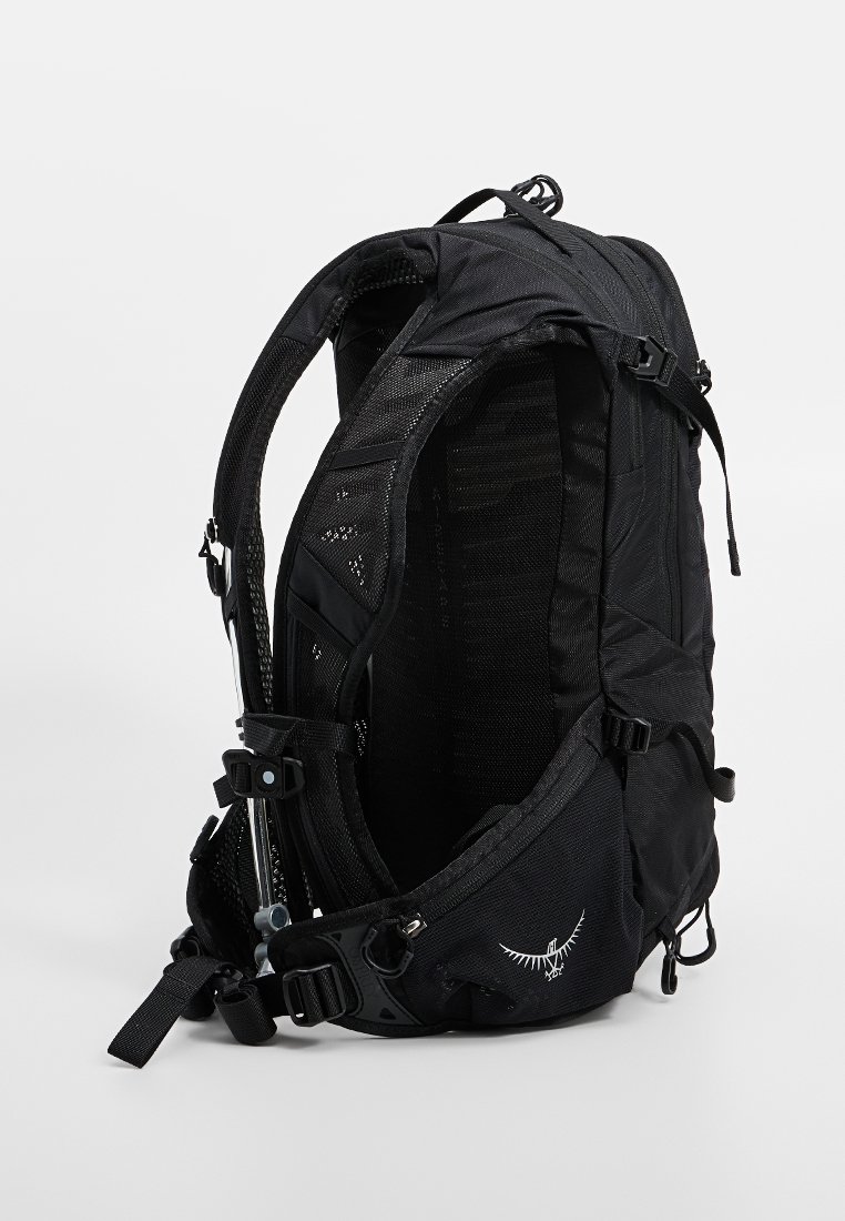 Mochila negra con un diseño de malla, correas ajustables y múltiples compartimentos. Cuenta con cremalleras y un logo en la base. Material ligero.