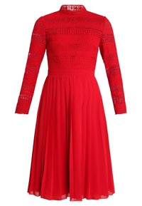 Röd klänning med långa spetsärmar, genomskinlig halsringning, mönstrad bodice och plisserad kjol, tillverkad av lättviktig tyg med en texturerad yta.