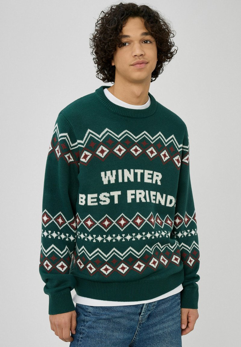 Pull vert en maille avec des motifs de fête en blanc et rouge, arborant le texte "WINTER BEST FRIEND" sur la poitrine. Manches longues et col rond.