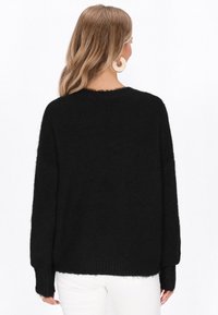 Czarny oversize sweter wykonany z miękkiego, puszystego materiału. Posiada okrągły dekolt, opadające ramiona i ściągacze przy mankietach. Prosty design.