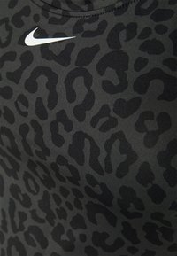 Leopardpatronen sportstof in tinten zwart en grijs, met een wit Nike-logo nabij de halslijn. Gladde textuur, aansluitend ontwerp.
