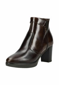 Bottes chelsea en cuir marron avec une texture lisse, bout pointu et talon épais. Elles présentent un panneau élastique sur le côté et des accents de design minimalistes.