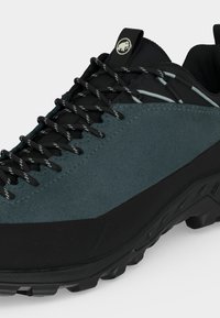 Mustade ja tumeroheliste matkajalanõude lähedalt vaade, millel on mustriga paelad ja robustne tald välioludeks.