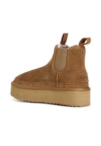 Cizmă la glezna din suede maro, cu panouri elastice pe laterale, căptușeală moale și o talpă platformă groasă, texturată. Buclă la spate pentru o îmbrăcare ușoară.