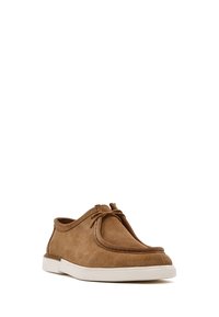 Chaussures en suède marron avec un bout rond, des détails en dentelle et une semelle en caoutchouc blanc. Texture lisse et coutures discrètes soulignent le design.