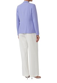 Lichtpaarse op maat gemaakte blazer met een slim fit, geknipte revers en gestructureerde schouders, gecombineerd met brede witte broeken.