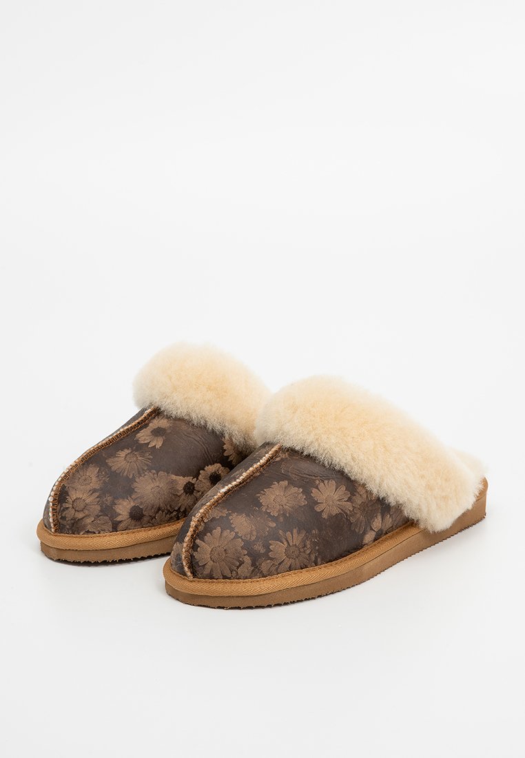 Bruine slippers met een bloemenpatroon en een zachte beige bontboord. Beschikt over een textuur op het oppervlak en een tan kleurige zool. Rond neusdesign.