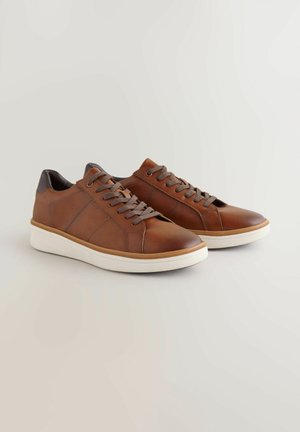 Brązowe skórzane sneakersy z szarymi akcentami, płaska biała podeszwa, okrągły czubek i okrągłe sznurowadła. Charakteryzują się kontrastowym wzorem paneli po bokach.