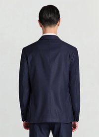 Veste de costume bleu marine ajustée avec un tissu texturé. Deux fentes arrière, revers lisses et ornements de boutons sur les manches.