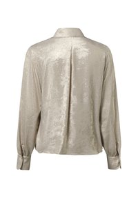 Rückansicht einer langärmligen, hellbeigen Satinbluse mit zentraler Falte und geknöpften Manschetten.