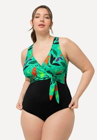 Maillot de bain une pièce avec un haut à imprimé floral vert vif et un bas noir. Doté d'un décolleté en V et d'un détail de nœud à l'avant.