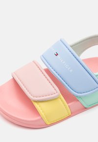 Sandal s pastelovými barvami v růžovém, modrém, žlutém a zeleném designu; syntetický materiál; nastavitelné popruhy; logo na modrém popruhu.