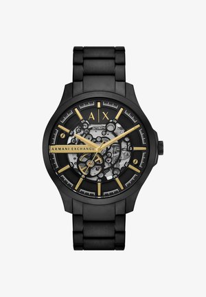 Zwart metalen Armani Exchange polshorloge met goudkleurige wijzers en markers, skelet-wijzerplaat die de mechanische beweging toont, en automatische label.