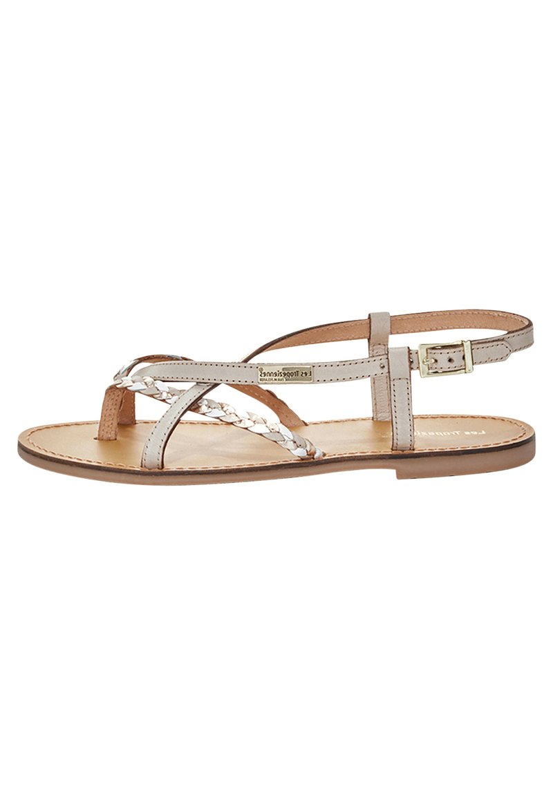 Sandalo in pelle beige chiaro con cinturini intrecciati, punta aperta e cinturino alla caviglia regolabile con fibbia dorata. Suola piatta.