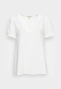 Biała bluzka z krótkimi, bufkami i dekoltem w kształcie litery V. Wykonana z lekkiego materiału o lekko teksturowanym wykończeniu i falbaniastych krawędziach rękawów.