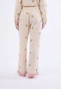 Vloeiende, crèmekleurige broek met verticale strepen en bloemenborduursels. Kenmerkt zich door roze boorden aan de zoom en een ontspannen pasvorm.