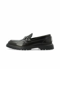 Mocasines de cuero negro con punta redonda, detalle de costura y un acento metálico decorativo. Suela de goma gruesa para tracción y durabilidad.