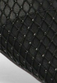 La tela de malla negra presenta un patrón de diamantes, embellecido con pequeñas cuentas brillantes integradas en el diseño para añadir textura y detalle.