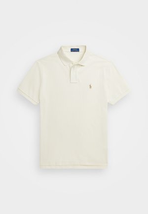 Polo tričko s krátkym rukávom v svetlej krémovej bavlnene, s klasickým golierom, trojicou gombíkov a vyšitým logom na ľavej strane hrude.