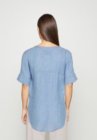 Chemise en lin bleu clair à manches courtes et ourlet arrondi, avec un design simple et décontracté. Texture lisse avec une apparence respirante.
