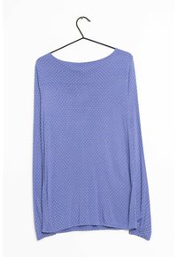 Blusa de manga larga, de color púrpura claro, hecha de un tejido suave, con un escote redondo y un patrón de lunares blancos en toda la prenda. Cuelga de un gancho negro.