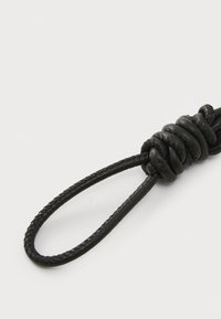 Anello in pelle nera con design annodato, caratterizzato da una texture liscia e sottili fili intrecciati. Accessorio semplice e funzionale.