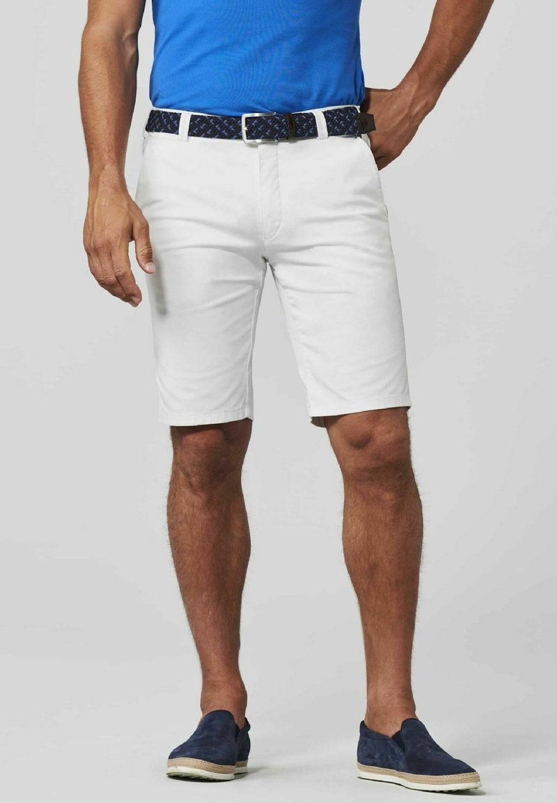 Witte katoenen shorts met een rechte snit, gedragen met een blauwe shirt en een patroon van een donkerblauwe riem. Donkerblauwe instappers ronden de look af.