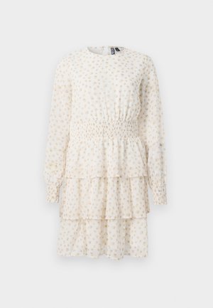 Robe à volants en crème clair avec un petit motif floral beige. Présente des manches longues et une taille smockée pour une silhouette ajustée.