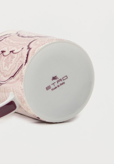 Tasse en céramique blanche avec des motifs ornés roses et une anse bordeaux, affichant la marque "ETRO Made in Italy" au fond.