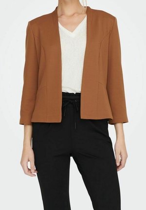 Woman wearing a brown open-front blazer, white V-neck top, and black drawstring pants, shown from neck to hips against a white background.