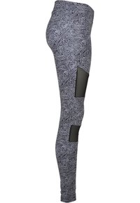 Tights i et svart og hvitt labyrintmønster med høy midje og nettingpaneler på knærne, laget av elastisk materiale.