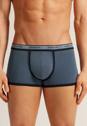 Boxers en tissu bleu foncé pour homme, avec une taille contrastante noire portant un logo, texture douce et design soutenant avec des coutures verticales.