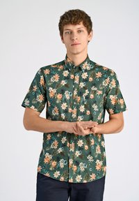 Camicia a maniche corte realizzata in tessuto con una base verde, caratterizzata da un motivo floreale in arancione, giallo e bianco con tocchi di foglie.
