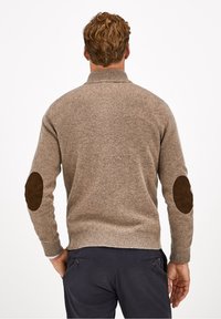 Brauner Wollpullover mit einem hohen Kragen und gerippten Bündchen. Auffällige braune Wildleder-Patches an den Ellenbogen beider Ärmel. Schlichte Stricktextur.