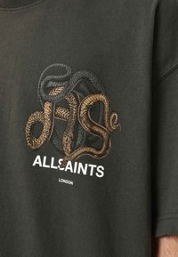 Czarna koszulka z grafiką splecionych węży w kolorze złotym i czarnym, poniżej wzoru nadruk "ALLSAINTS" w białym kolorze.