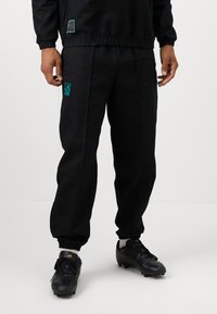 Zwarte sportbroek met een elastische tailleband, joggermanchetten en een turquoise geborduurd logo op de dij; gemaakt van duurzaam materiaal.