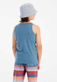 Blauwe mouwloze shirt met een gladde textuur, gecombineerd met multicolore patroon shorts met horizontale strepen in rood, blauw en oranje.