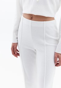 Witte gebreide loungewear set met een cropped top en hoge taille broek van textuurstof en contrasterende zijnaden.