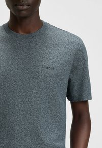 Grå kortærmet T-shirt lavet af tekstureret stof med rund halsudskæring. Har et diskret "BOSS" logo i sort på brystet.
