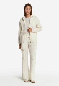 Vit kabelstickad tröja med huva, ihop med en matchande rundhalsad topp och vida byxor, med ribbade kantar och nederkant.