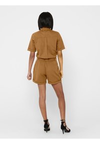 Combinaison brune à manches courtes avec une taille cintrée et un ourlet retroussé aux shorts. Vue arrière montrant un design simple avec un col droit et sans ornements.